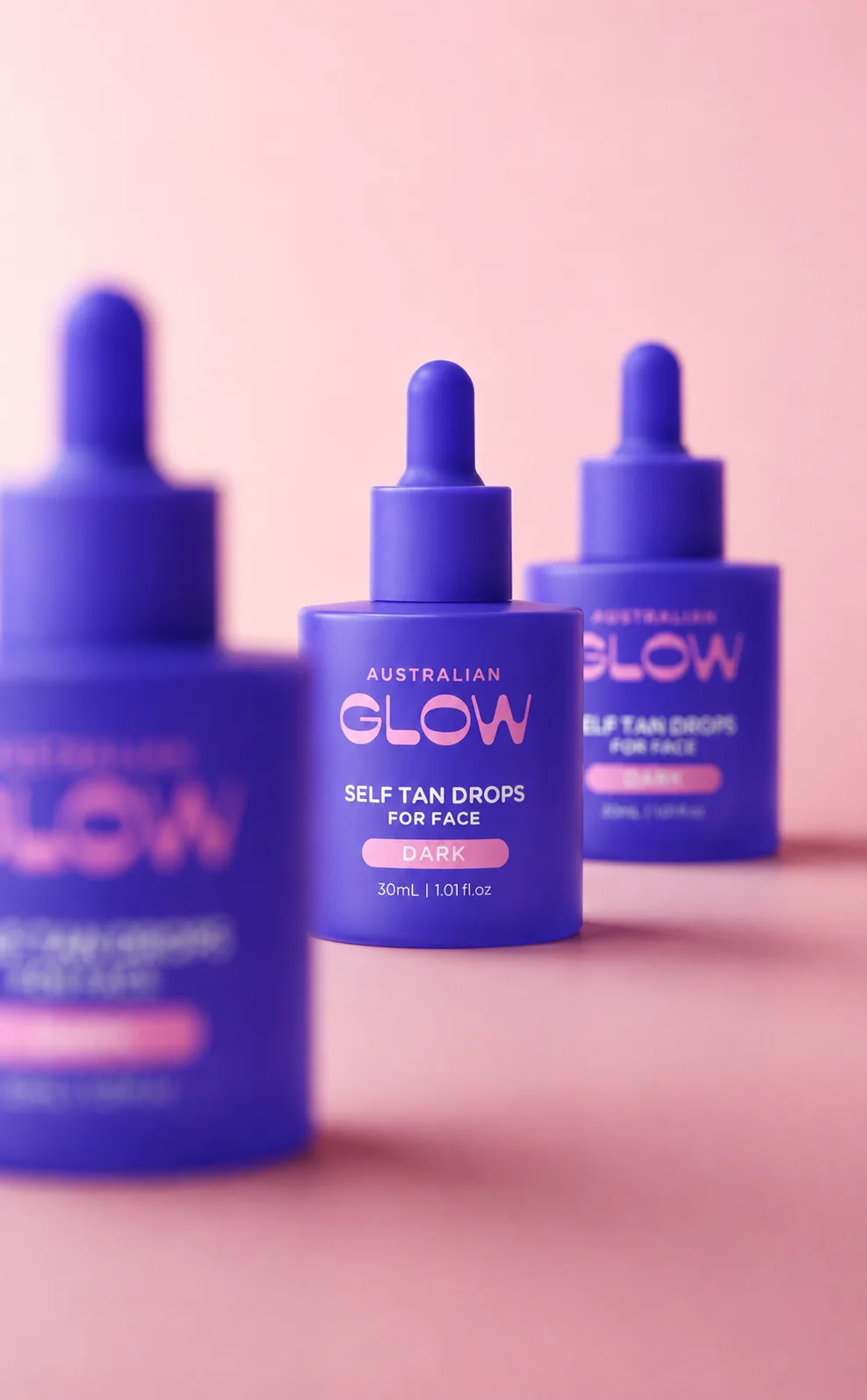 Face Tan Drops trio on a pink campaign backdrop