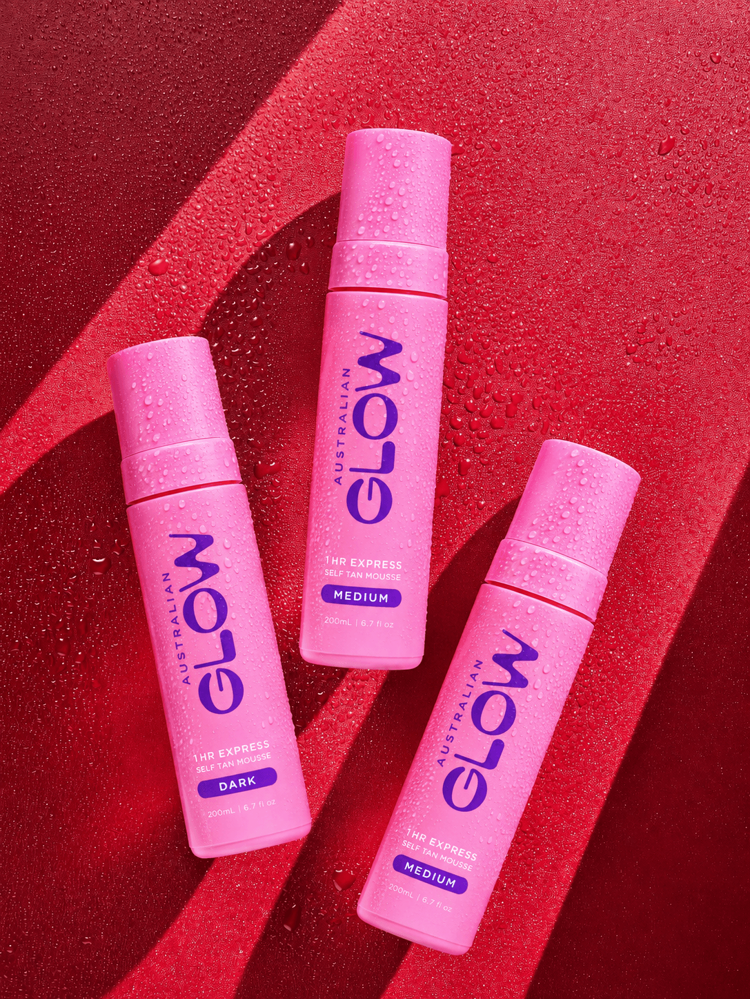 Australian Glow 1 Hour Express — three pink bottles laid across a wet red surface