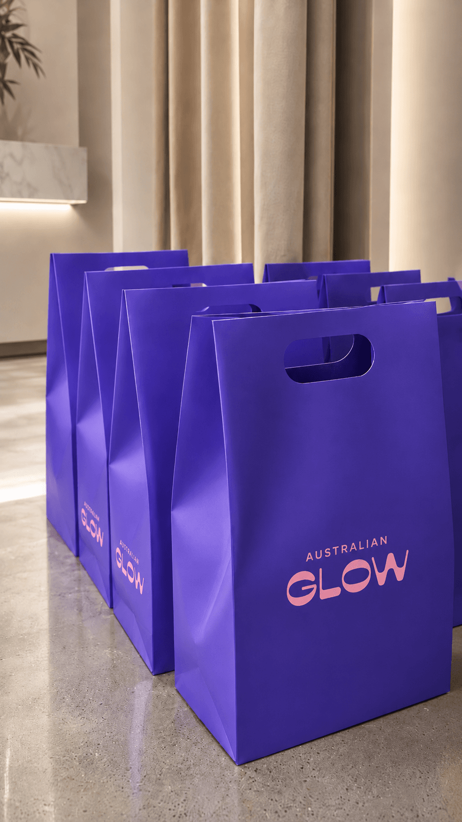 Australian Glow — rows of purple branded shopping bags lined up in a stone retail showroom